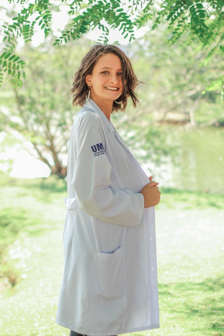 Foto informal da Evelyn Santos ao ar livre, de jaleco